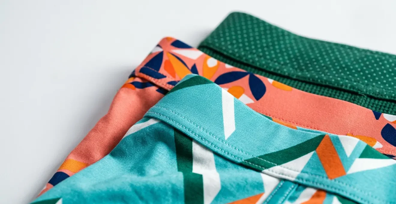 Gros plan sur des tissus de sous-vêtements masculins aux motifs variés et couleurs vives disposés avec soin
