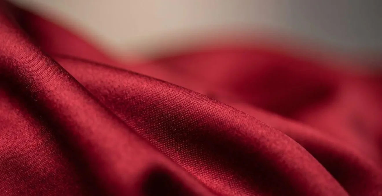 Gros plan détaillé d'une matière satinée rouge révélant sa texture et son tombé luxueux