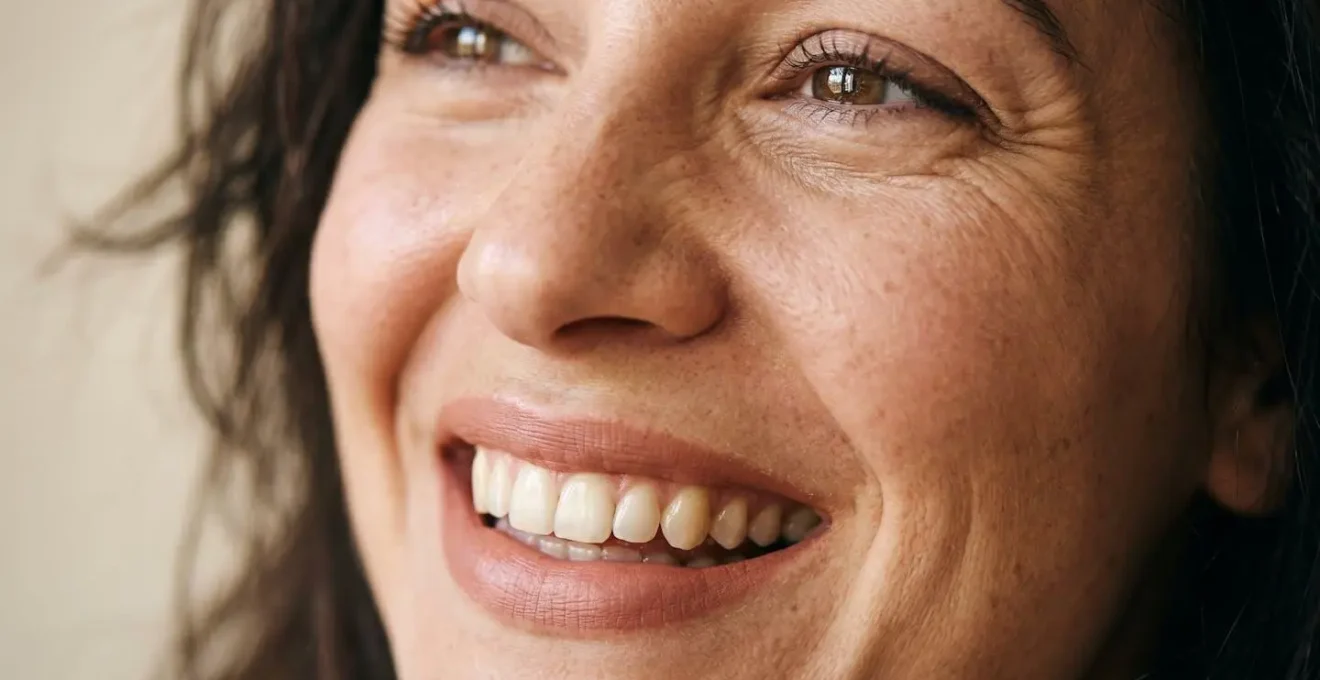 Gros plan sur un visage feminin exprimant un sourire sincere et lumineux dans une lumiere naturelle douce